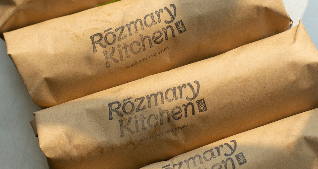 Sandwiches wrapped in brown butcher paper, stamped with Rozmary Kitchen logo